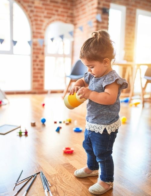 Toddler standing and playing with a sensory toy during natural developmental play